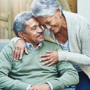 Elderly couple smiling and embracing each other outdoors, conveying love and companionship in a joyful moment